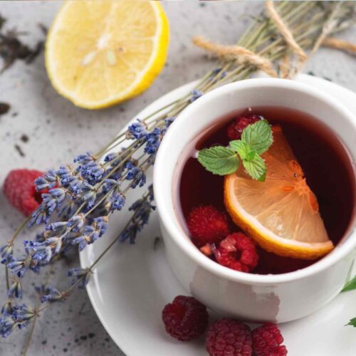 A cup of red raspberry leaf tea with a lemon and lavender.