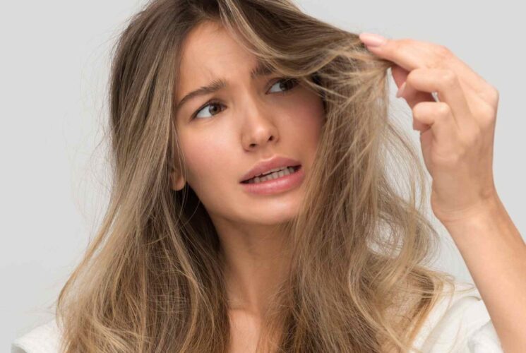 A woman holding out her damaged hair because she didn't use paraben free shampoo.
