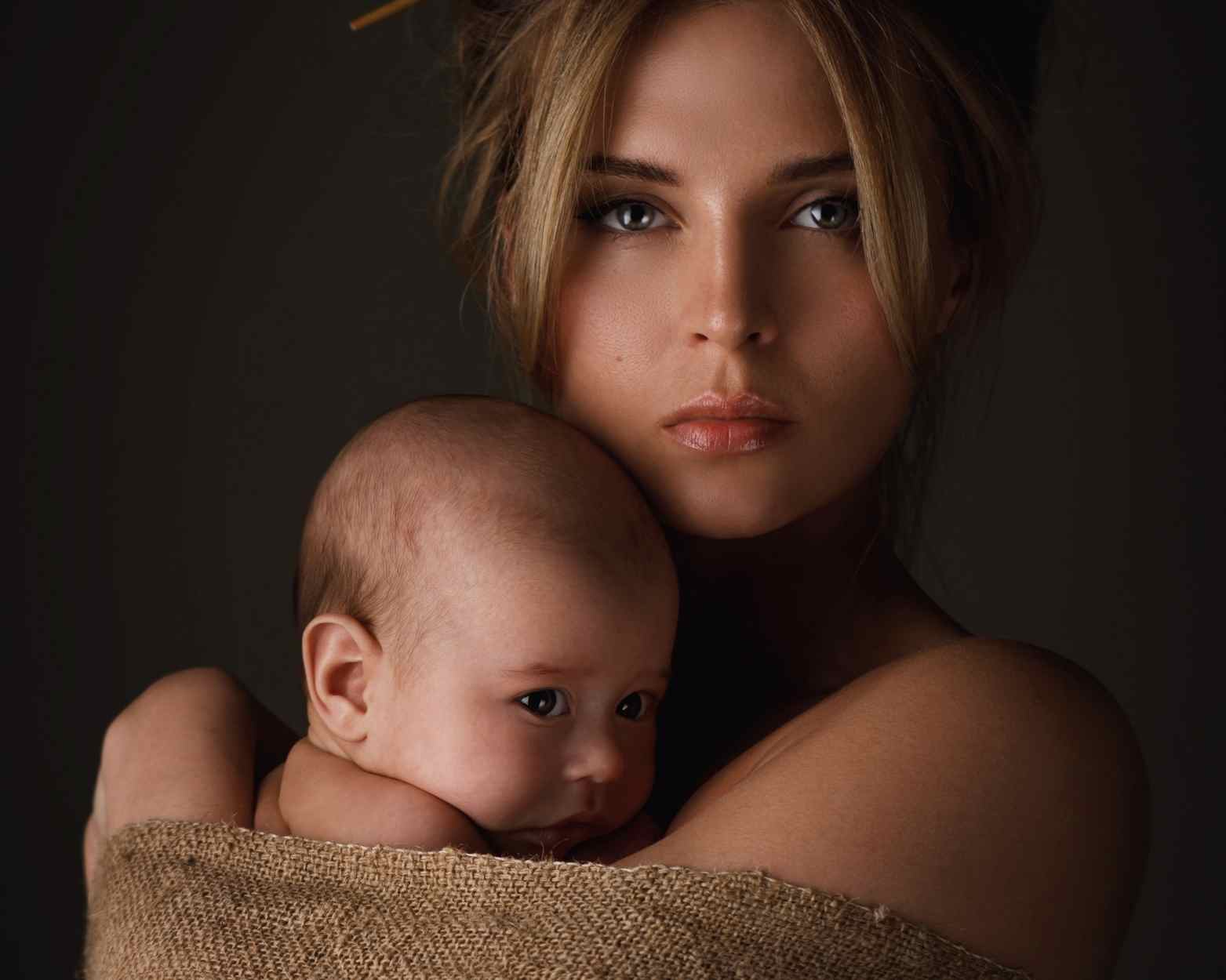 A postpartum woman dealing with her postpartum hormones and holding her newborn baby.