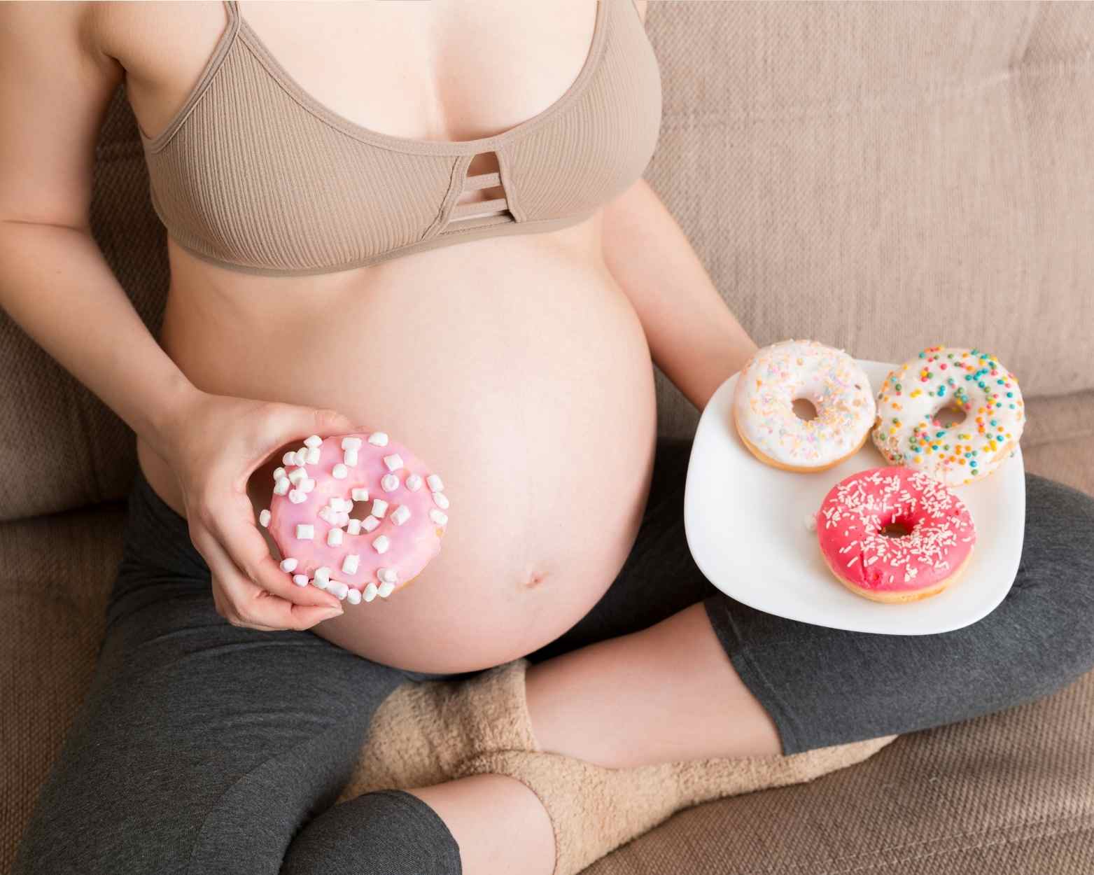 A pregnant woman holding donuts but wanting to have healthy pregnancy snacks instead.