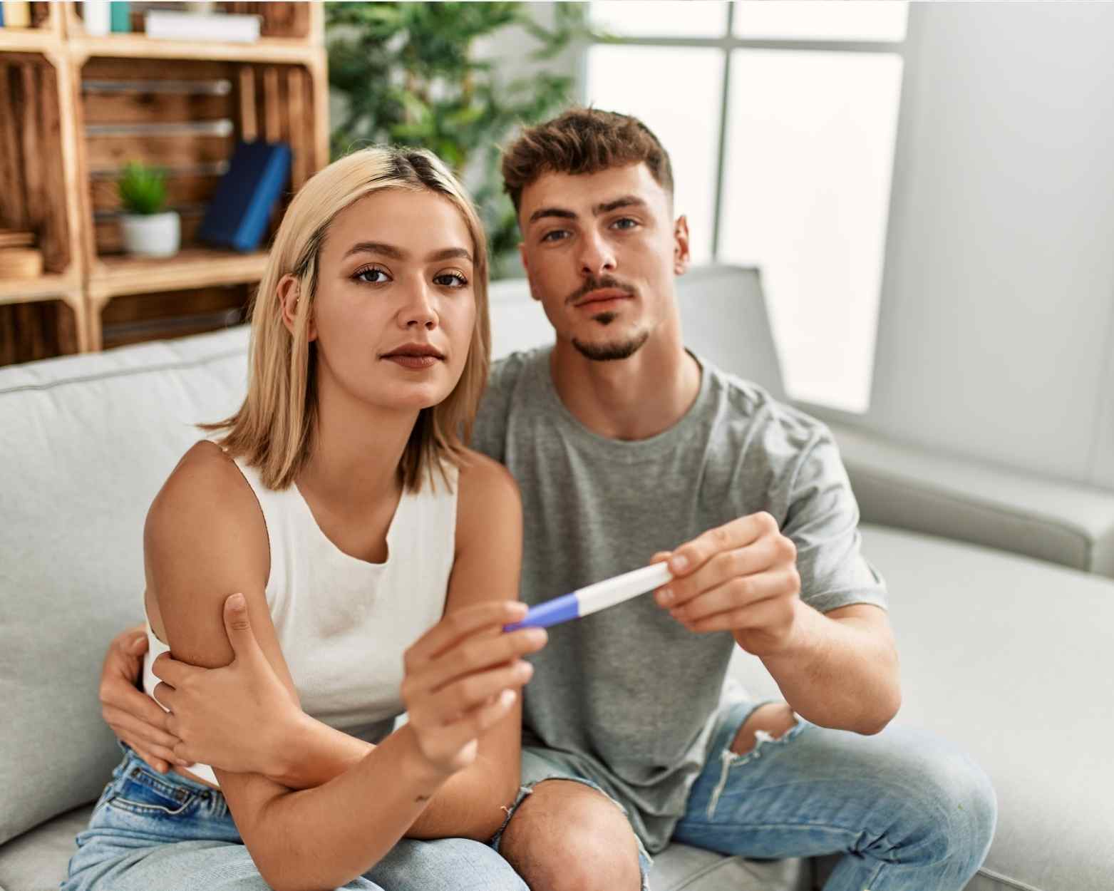 A man and woman wondering if they are pregnant and looking at a pregnancy test.