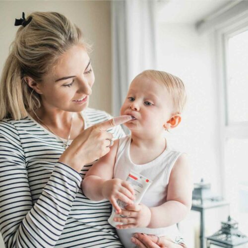 A mom helping to relieve her baby teething pains with natural teething pain relief methods.