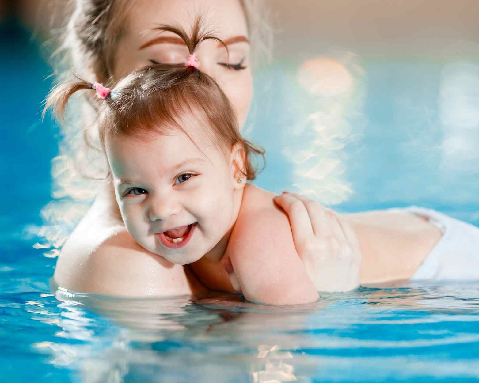A baby girl doing swimming lessons with her mom.