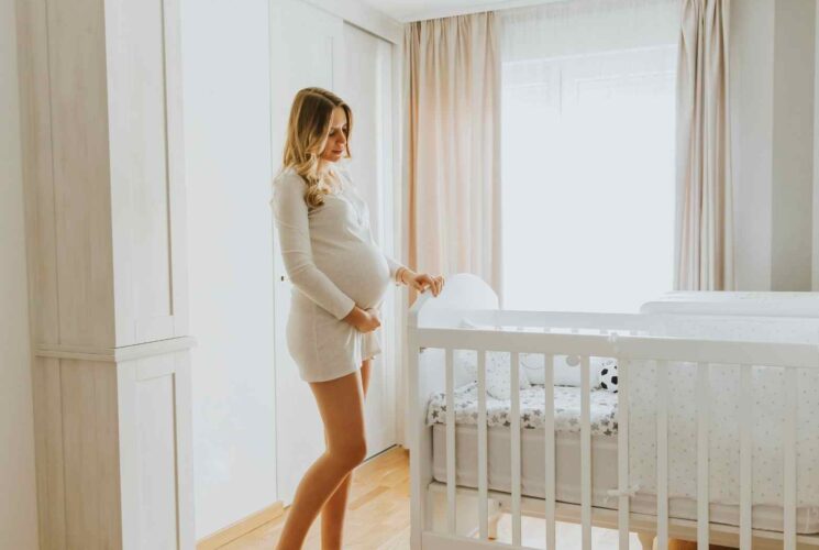 A pregnant mom standing in her baby's nursery and getting her home ready to bring baby home.